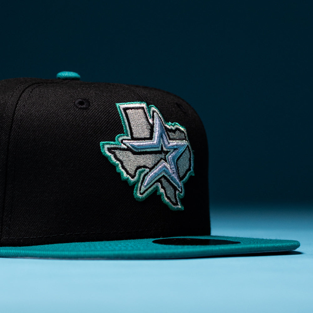 Certainly! Here’s a rewritten sentence using the provided product data: The Silver Lining Black Teal 2000 Houston Astros New Era 5950 Fitted Hat showcases an embroidered outline of Texas with a striking star design on the front, channeling the bold spirit of the Astros. This cap is set against a blue background.
