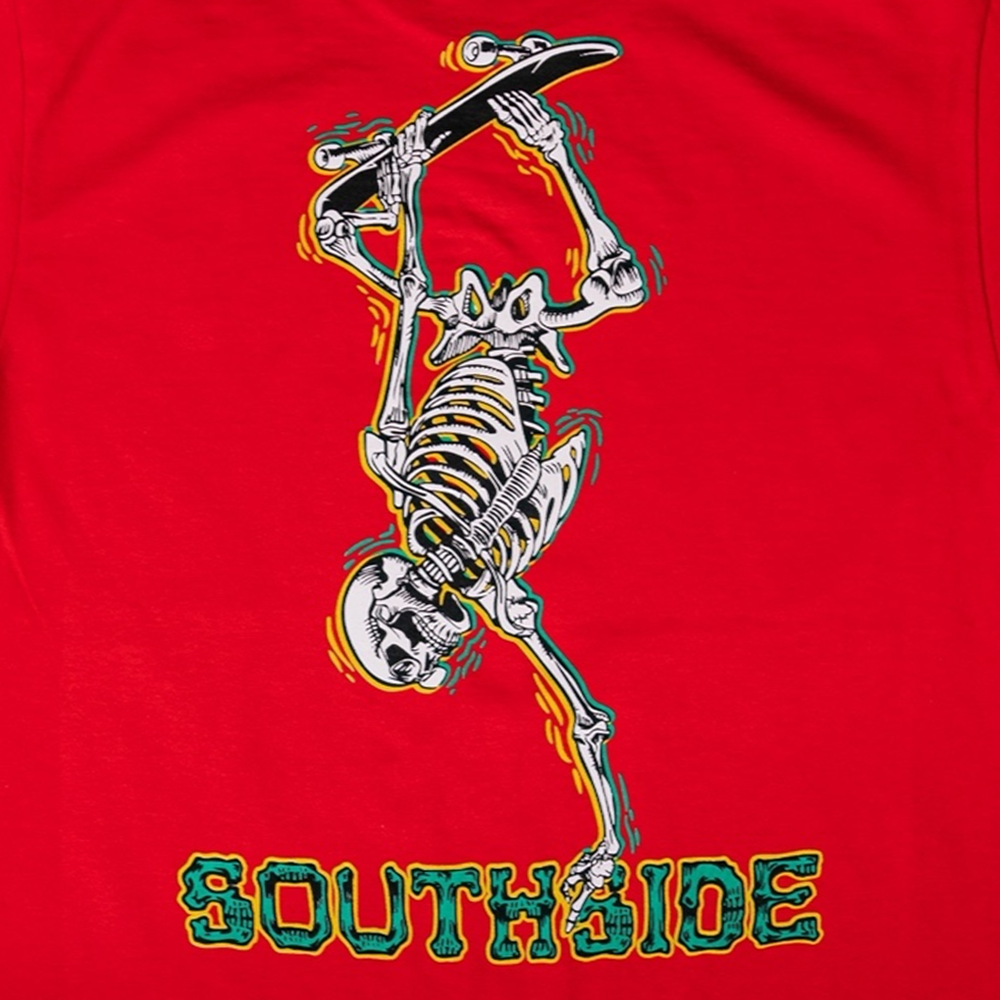 A graphic of a skeleton handstanding on a skateboard, outlined in yellow, blue, and green above "SOUTHSIDE" in bold green and yellow on red. Bones Pack Ben Raybourn Red Southside Skatepark Tee on premium USA cotton.
