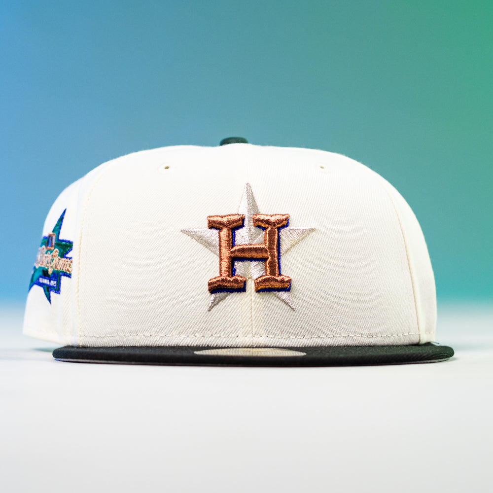 The Houstatlantavegas Chrome Black Green ASG Houston Astros New Era 5950 Fitted Hat features a white crown, black brim, gold H over a star on the front, colorful side patch, and is inspired by the Astros. Background: blue and green gradient.