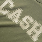 A close-up of the Campus Tee Olive Cash Only, a heavyweight cotton tee in olive green (6.5oz fabric), featuring "CASH" in bold, white outlined block letters screenprinted across the chest.