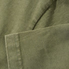 Close-up of Campus Tee Olive Cash Only’s 6.5oz heavyweight cotton fabric, showing visible stitching, a neatly sewn edge, and a smooth, slightly textured olive green surface.