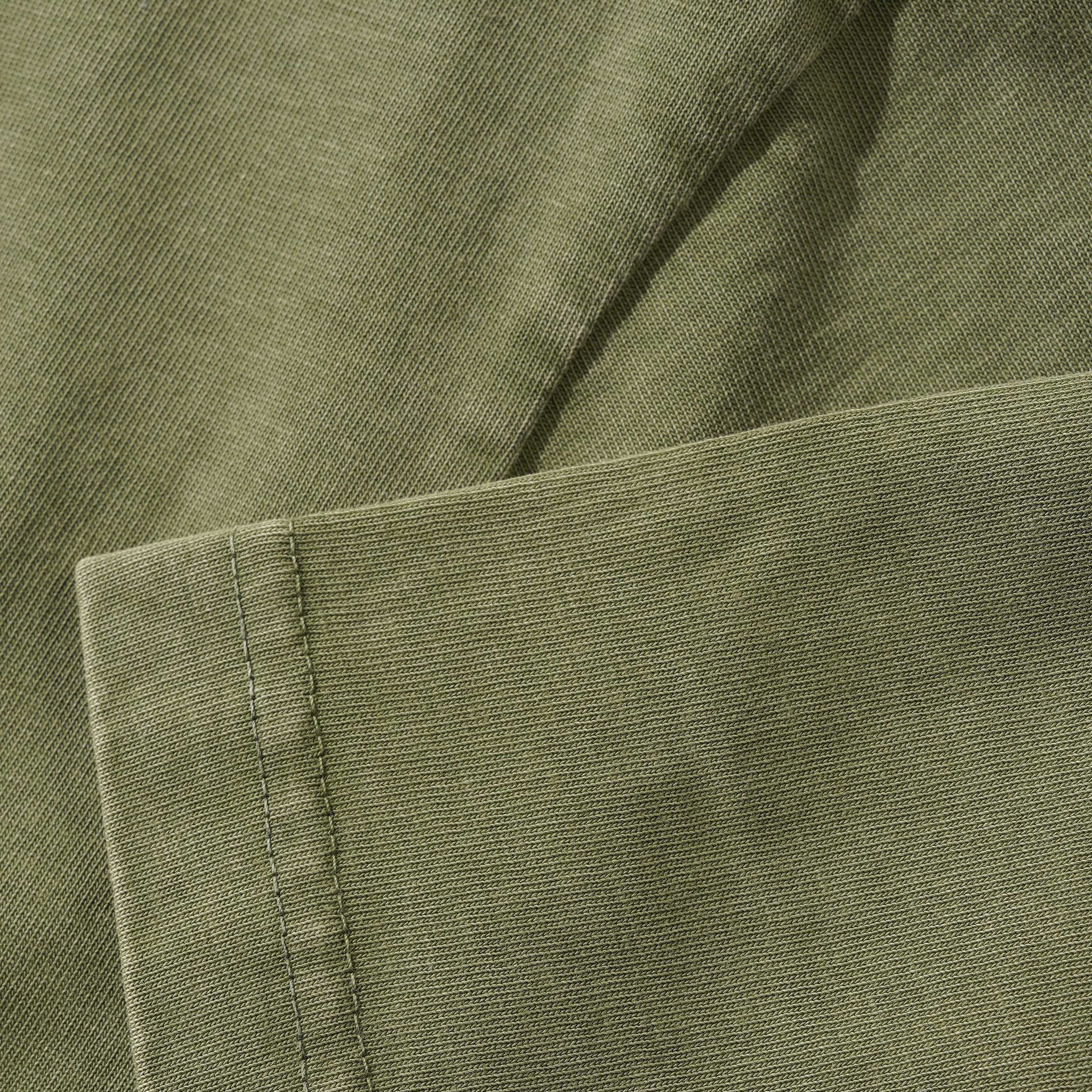 Close-up of Campus Tee Olive Cash Only’s 6.5oz heavyweight cotton fabric, showing visible stitching, a neatly sewn edge, and a smooth, slightly textured olive green surface.