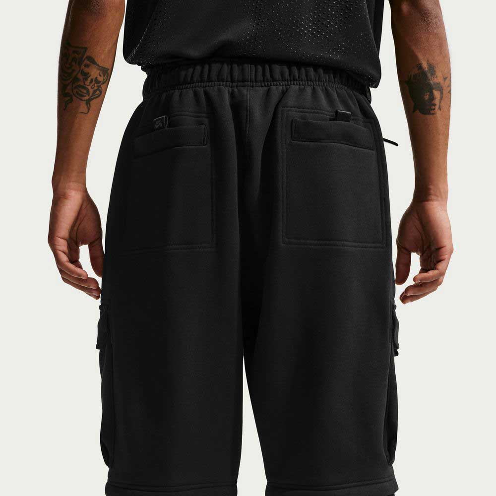 A person shown from the back wears black Ishod Cargo Pant Sweatpant Black IF0659010 by Nike SB and a black top. The pants feature large back pockets, and both tattooed forearms are visible.