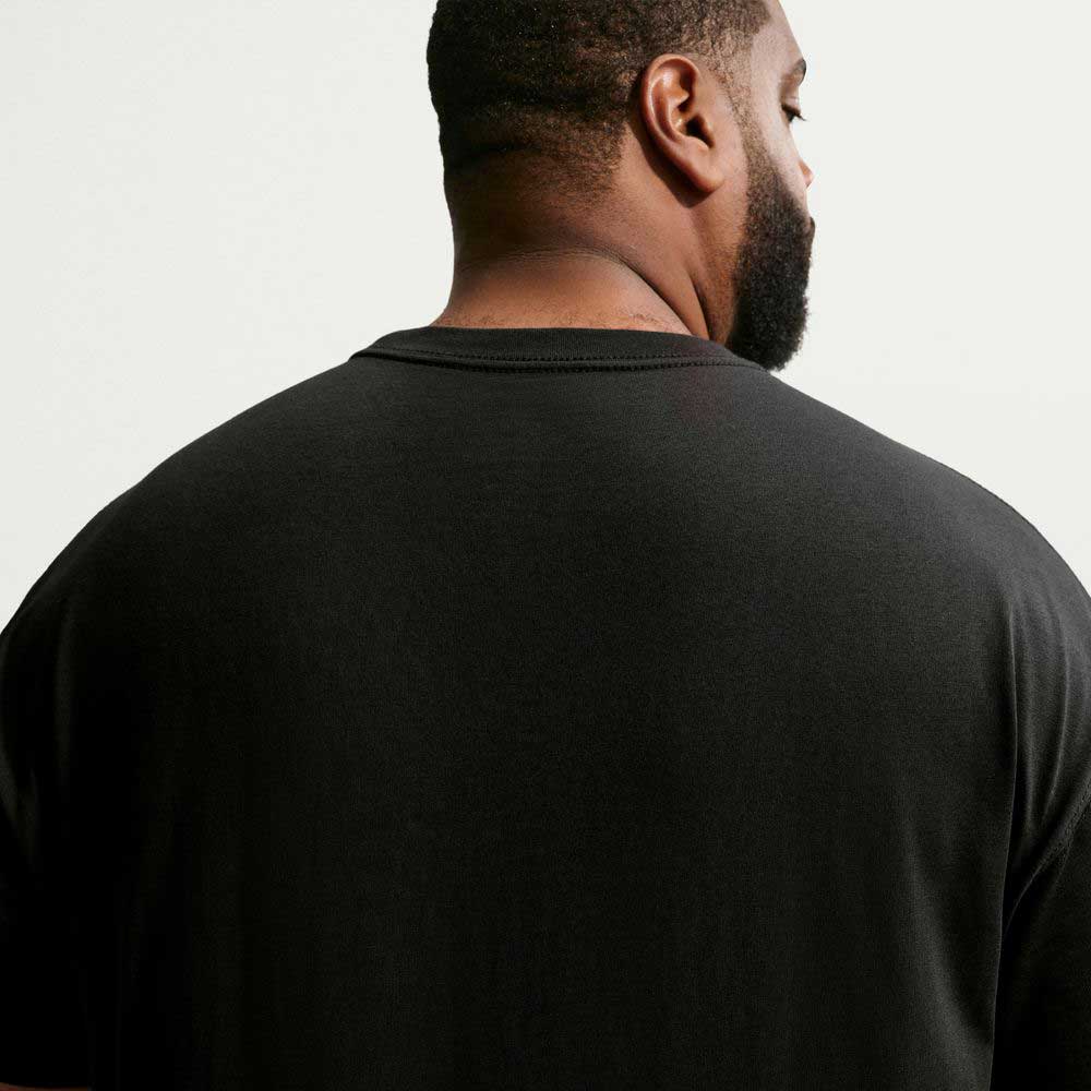 A man with short hair and a beard is pictured from behind, wearing the black Nike SB Cell Phone Tee (IM4424010), a skateboarding T-shirt, against a light background.