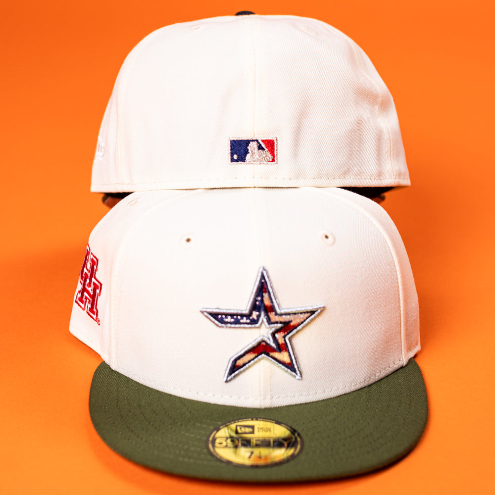Two white Stars Over Houston UH New Era Hat 5950 Fitted hats are shown on an orange background. The front cap displays a star logo with an American flag design and a green brim; the back shows a small MLB logo.