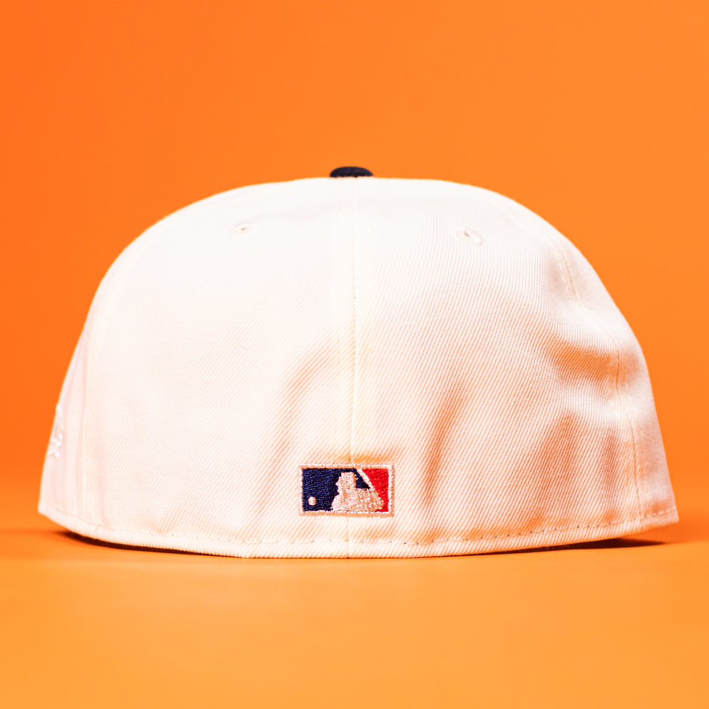 The Stars Over Houston UH New Era Hat 5950 Fitted is shown from the back, displaying a small embroidered MLB logo near the bottom, set against a bright orange background.