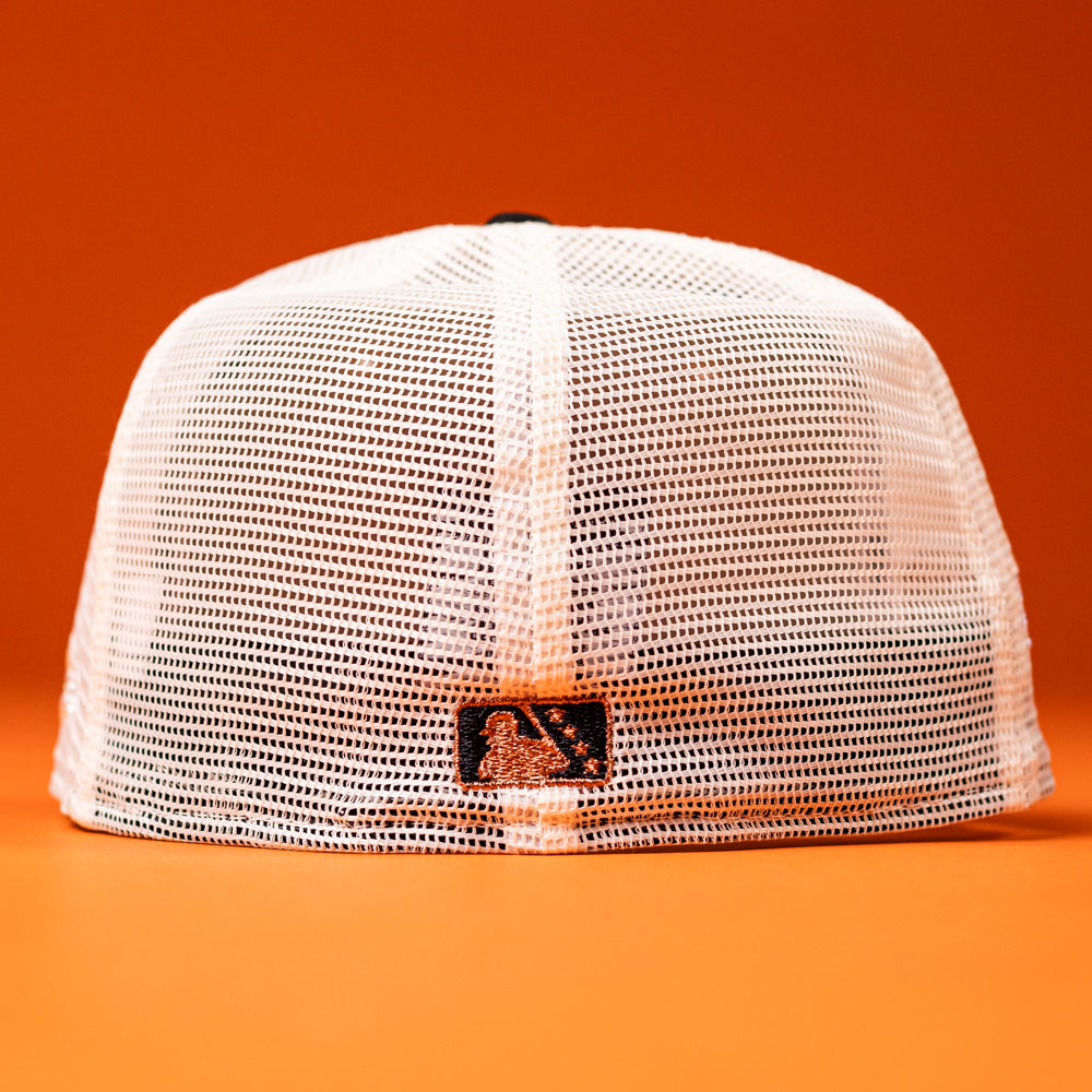 The Wrangler Chrome Rust Sugarland Space Cowboys New Era Hat 5950 Fitted is displayed from the back, highlighting a small MLB logo tag at the base. This white mesh baseball cap is crafted in the classic New Era 5950 fitted style and set against an orange background.