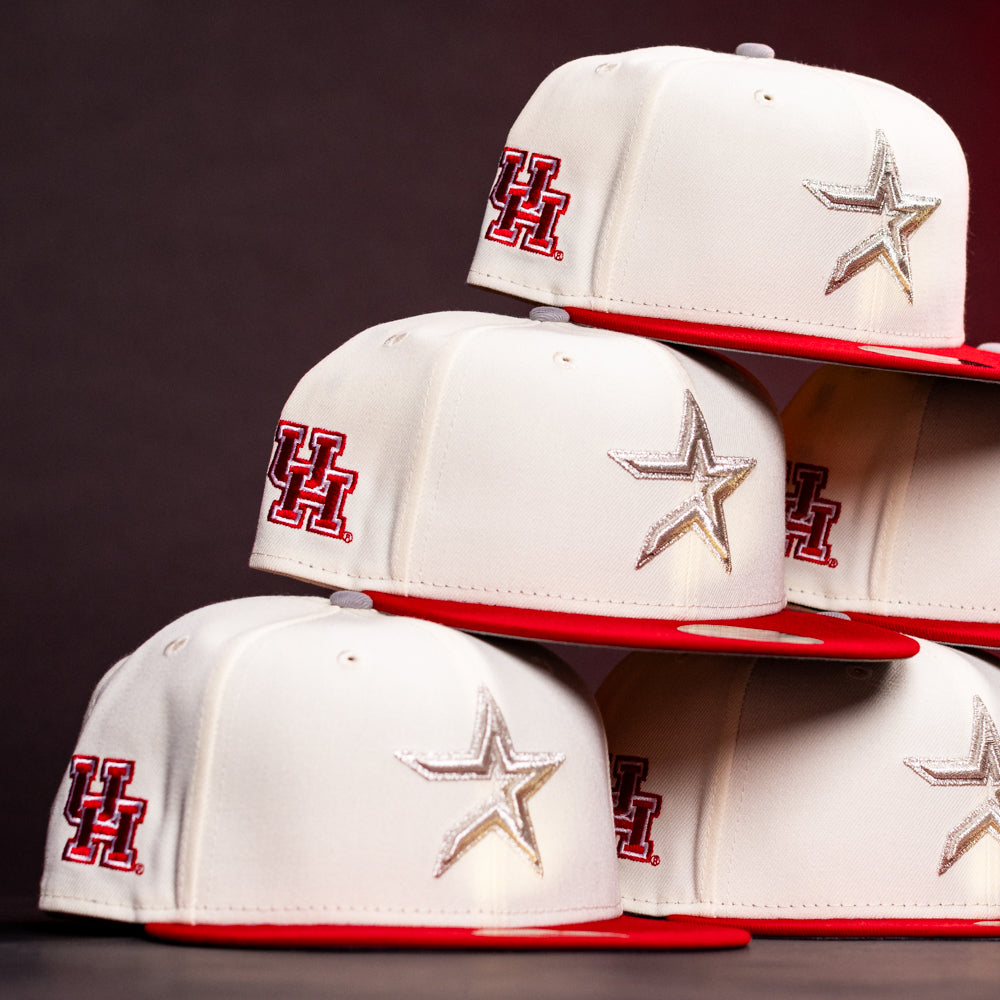 Stacked white and red “The Carter Chrome Scarlet Houston Cougars New Era Hat 5950 Fitted” caps, featuring a red UH logo on the side and a silver star on the front, are prominently displayed against a dark background.