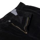Close-up of Classic 87 Corduroy Cargo Pant Black Spitfire Wheels, showing the open zipper and button, with a white fabric label featuring a black wavy line pattern inside the waistband.