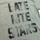 The College Tee Olive Late Nite Stars Screenprinted features wrinkled olive fabric and large, faded black "LATE NITE STARS" text across three lines, reminiscent of a classic college tee.