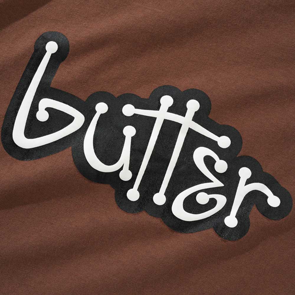 The Connection Brown Tee by Butter Goods features the word "butter" in a playful white font with rounded ends, outlined in black, set against brown fabric.