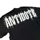 The Cropped White Shoulder Antidote Black Tee is an oversized black shirt made from 100% USA cotton, with bold, spiky "ANTISOCIAL" lettering in white across the back for a standout streetwear look.