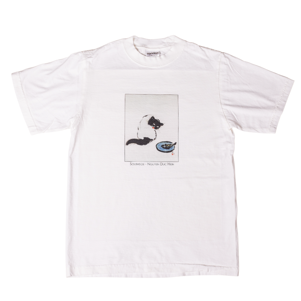 The Curious Cat Southside White Tee by Nguyen Duc Hien is made from USA cotton and features a black-and-white cat illustration above “SUMMER – NORTH DAK PARK.” Classic fit with a tear away label for comfort.