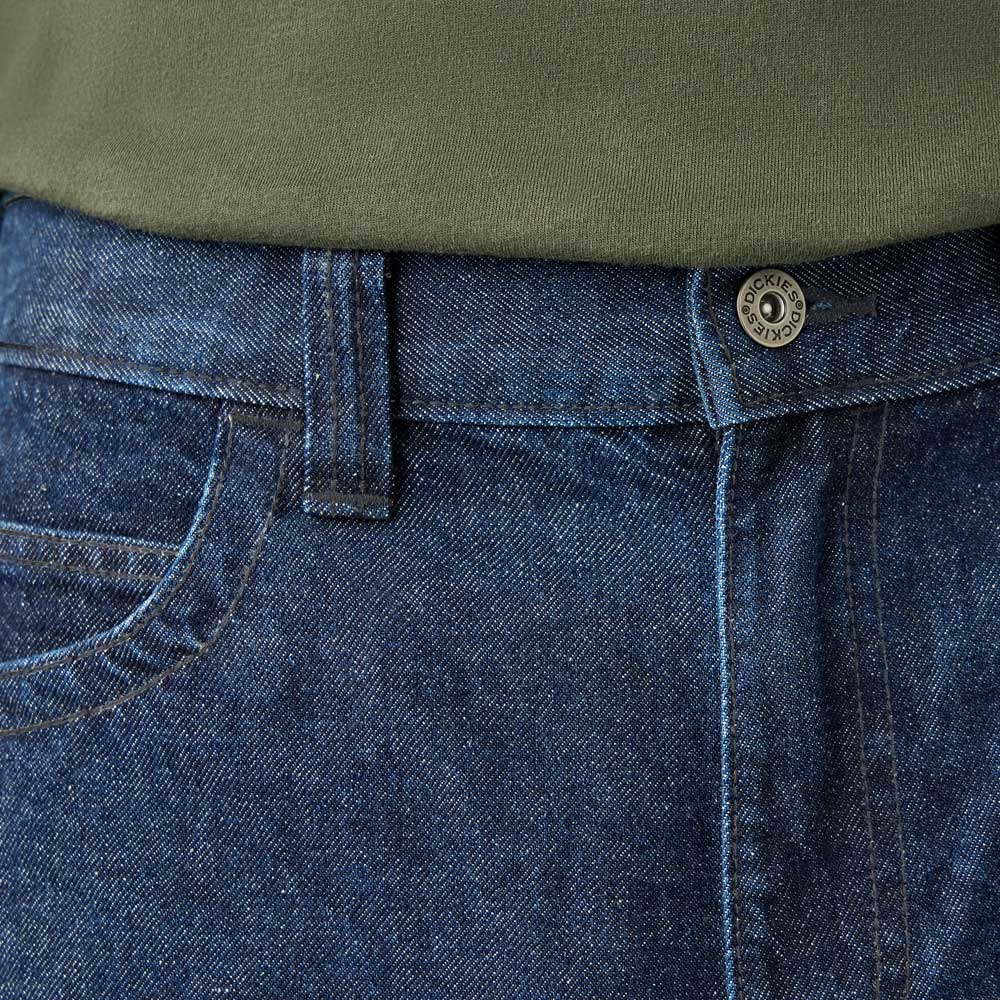Close-up of a person wearing DDSK68 Loose Fit Denim Pant Carpenter Dark Wash Dickies Skateboarding jeans with front pocket, belt loop, and metal button, paired with an olive green shirt tucked in at the waist.