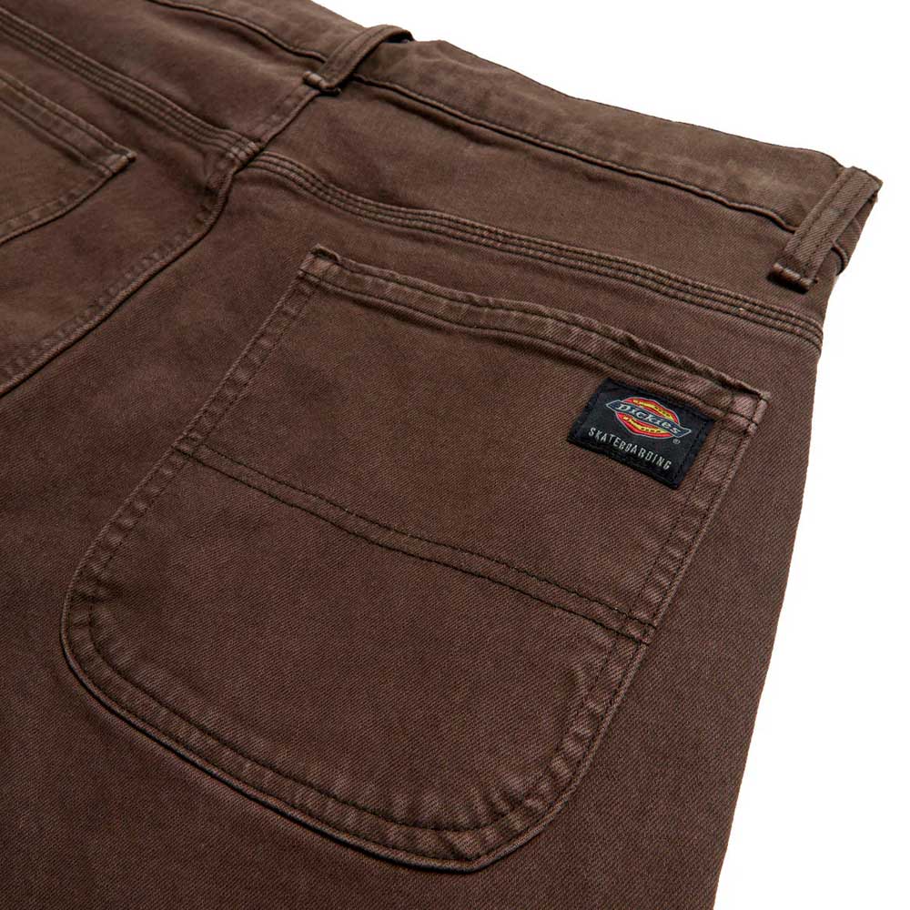 Close-up of DDSK68J84 Loose Fit Denim Pant in Wingville Brown Tint Wash by Dickies Skateboarding, highlighting the back pocket with sewn-on logo, detailed stitching, part of the waistband, and a belt loop.