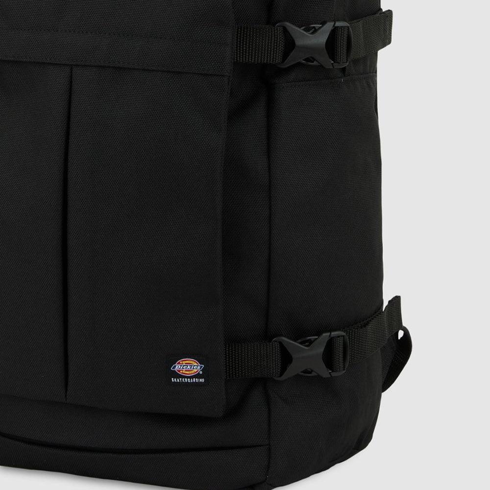 Close-up of the A8675BLK Black Mike Anderson Pro Skate Dickies Skateboard Strap Backpack with buckle skate straps and a small Dickies logo patch near the bottom, set against a light gray background.