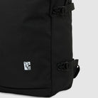 Close-up of the A8675BLK Black Mike Anderson Pro Skate Dickies Backpack featuring adjustable buckle straps, skateboard straps, and a small white rectangular patch with a minimalist llama drawing near the bottom corner.