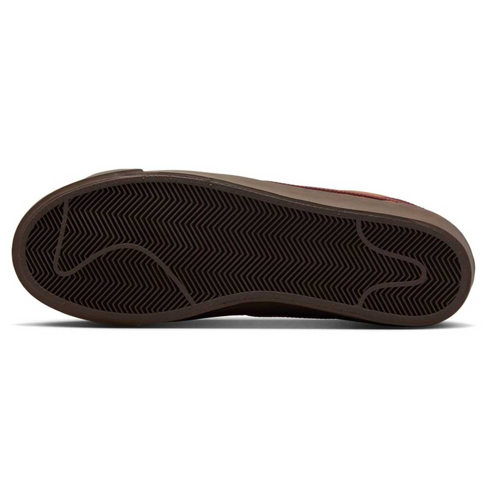 The image shows the bottom view of the DV1226200 GT Dark Red Brown Blazer Low Nike SB Suede Skateboarding Shoe, highlighting its dark, textured sole with a herringbone pattern and curved lines. The suede upper is partially visible along the edge.