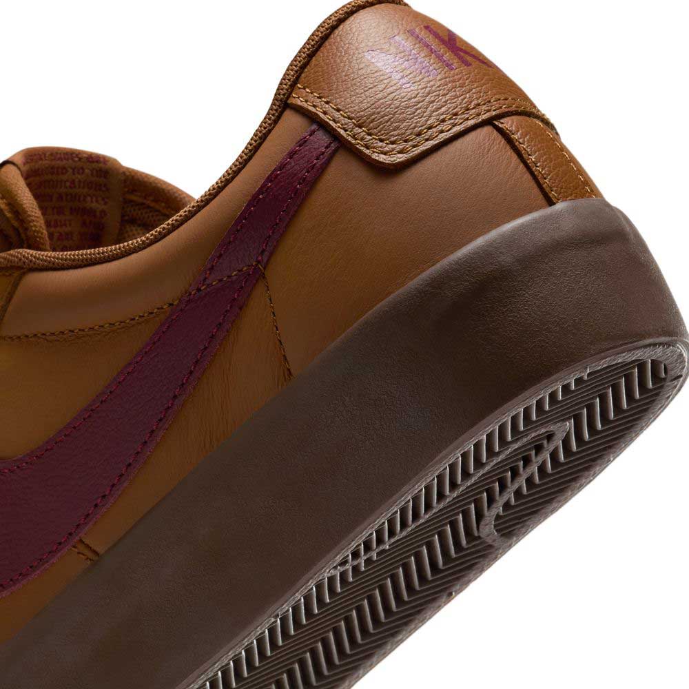 Close-up of the DV1226200 GT Dark Red Brown Blazer Low Nike SB suede skateboarding shoe with maroon swoosh, brown sole, textured tread, stitched heel detail, and subtle logo for classic skateboarding style.