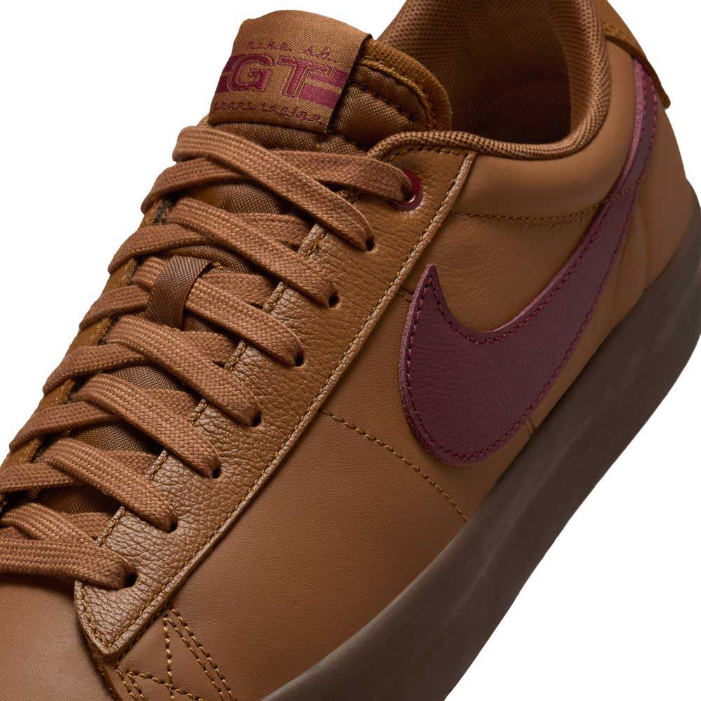 A close-up of the DV1226200 GT Dark Red Brown Blazer Low Nike SB skate shoe shows brown suede, maroon branding, brown laces and sole, stitched texture, and classic skateboarding style.