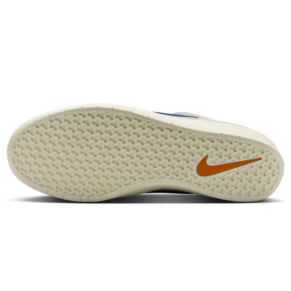 The image displays the sole of the DV5477-011 College Grey Racer Blue Light Orewood Force 58 Nike SB suede skateboarding shoe, featuring a textured, off-white rubber surface and an orange Nike Swoosh near the heel.
