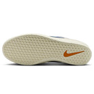 The image displays the sole of the DV5477-011 College Grey Racer Blue Light Orewood Force 58 Nike SB suede skateboarding shoe, featuring a textured, off-white rubber surface and an orange Nike Swoosh near the heel.
