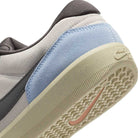 Close-up of the heel of the DV5477102 Light Orewood Brown Medium Aah Force 58 Nike SB suede skateboarding shoes, showing a pale blue suede panel, light beige textured cupsole, black Nike swoosh, and light gray fabric upper.