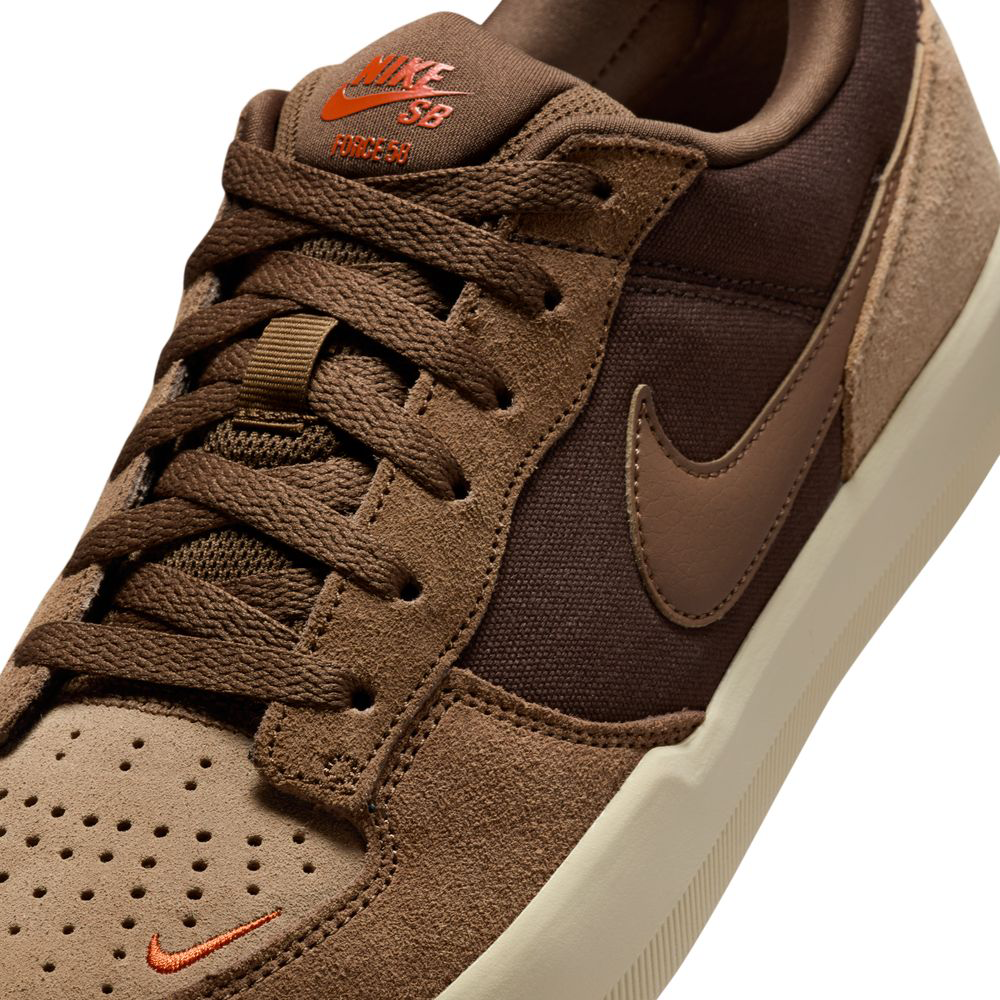 Close-up of the DV5477201 Baroque Brown Mosswood Brown Nike SB Force 58 skate shoe, featuring a suede and fabric upper, tan perforated toe, brown laces, orange embroidered Nike logo, and a cream rubber cupsole inspired by basketball DNA.