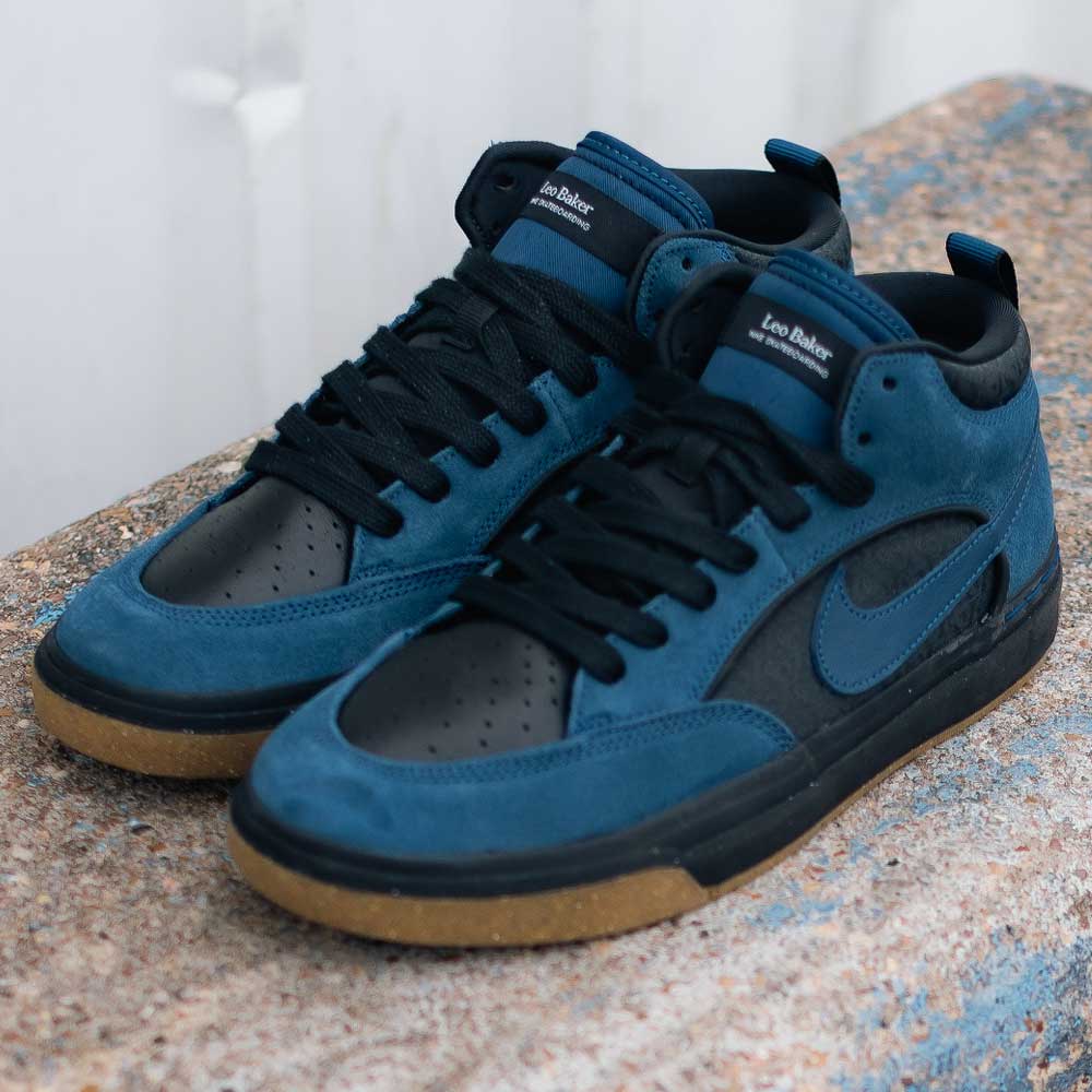 The DX4361401 Navy Black Anthracite Leo Baker React Nike SB skateboarding shoes feature blue suede overlays, black leather accents, black laces, and gum rubber soles, shown on a textured stone surface.