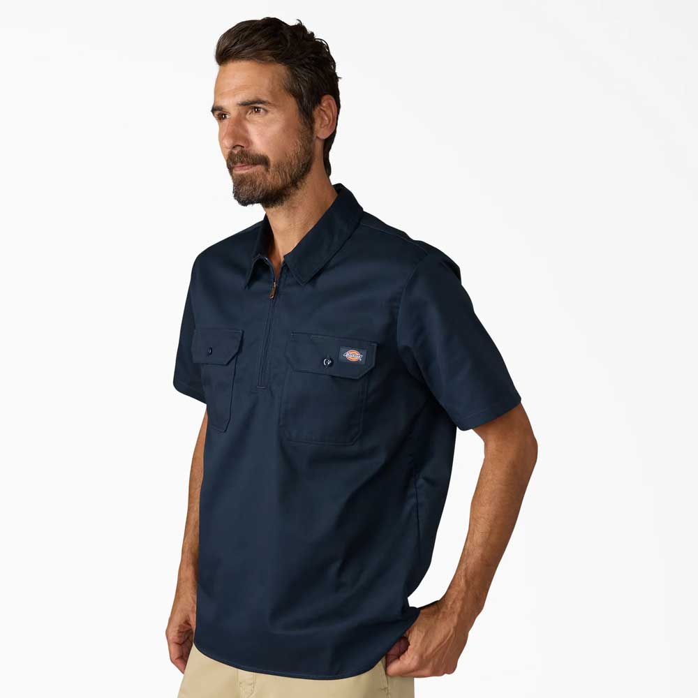 A man with short brown hair and a beard wears the Dickies Skateboarding Dark Navy 1/4 Zip Short Sleeve Work Shirt (A88A10DN) and beige pants, standing against a plain white background.