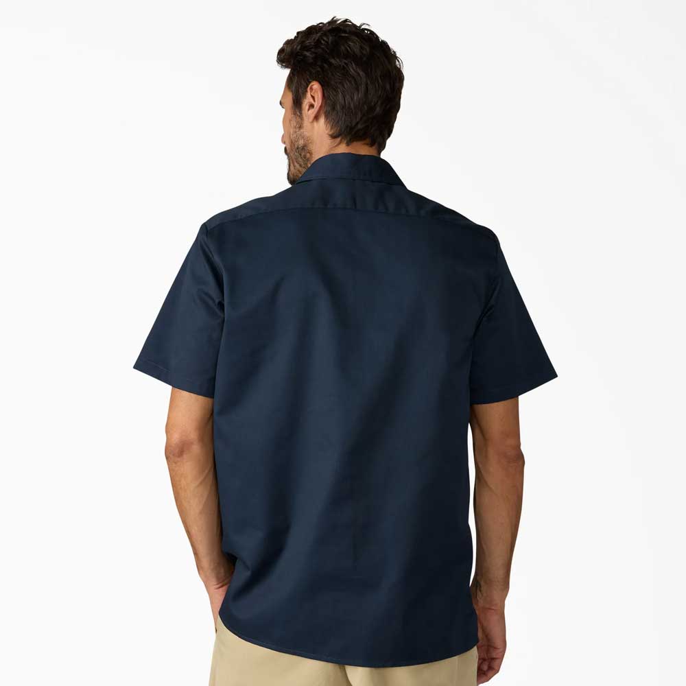 A man is seen from behind, wearing a Dickies Skateboarding Dark Navy 1/4 Zip Short Sleeve Work Shirt (A88A10DN) and light khaki pants against a plain white background.