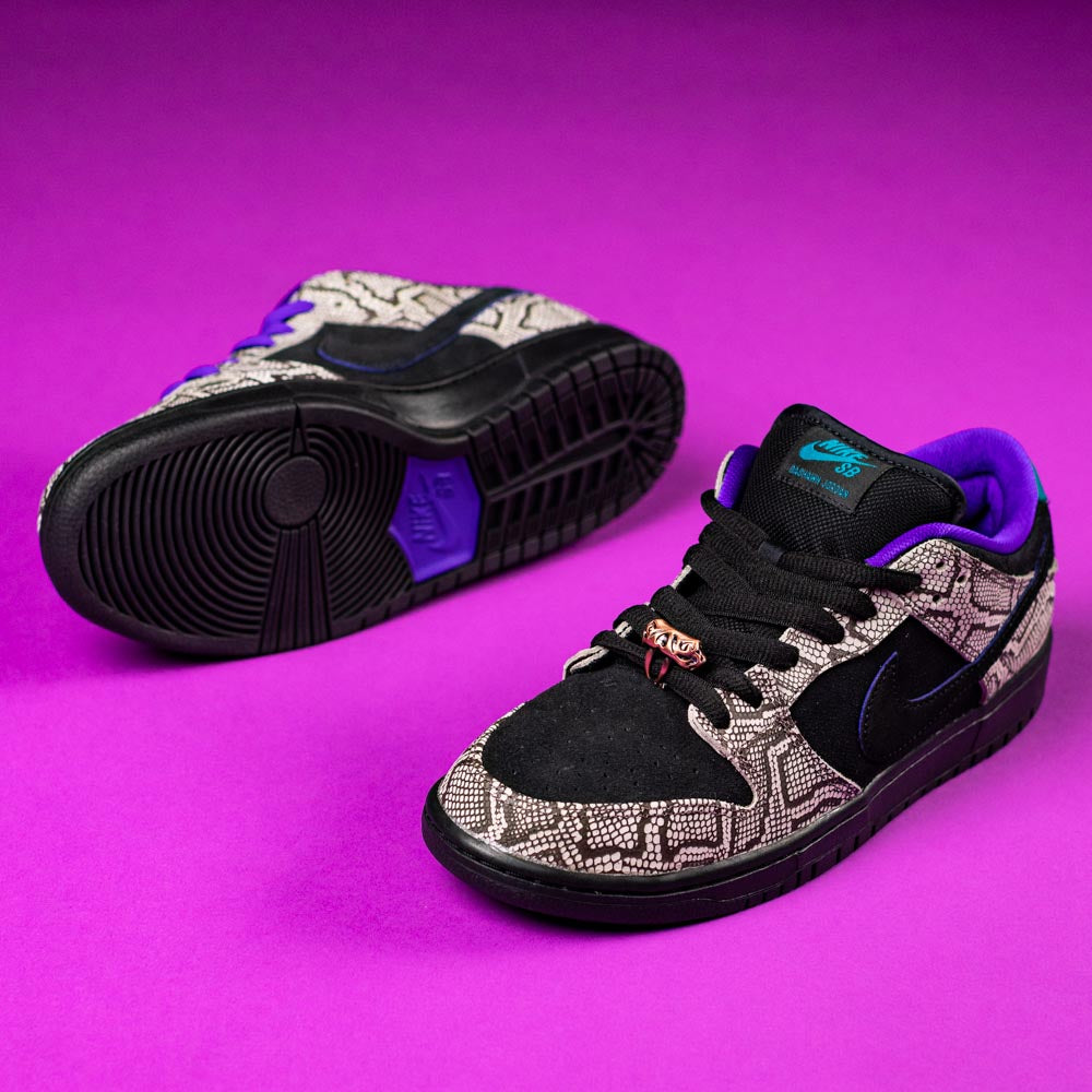 Two READ BELOW the BUTTON RAFFLE Nike SB Dashawn Jordan Dunk Low sneakers with black, white, and gray patterned uppers, black Swooshes, purple and teal accents, and black soles on a purple surface—ideal for Southside Skatepark or raffles.