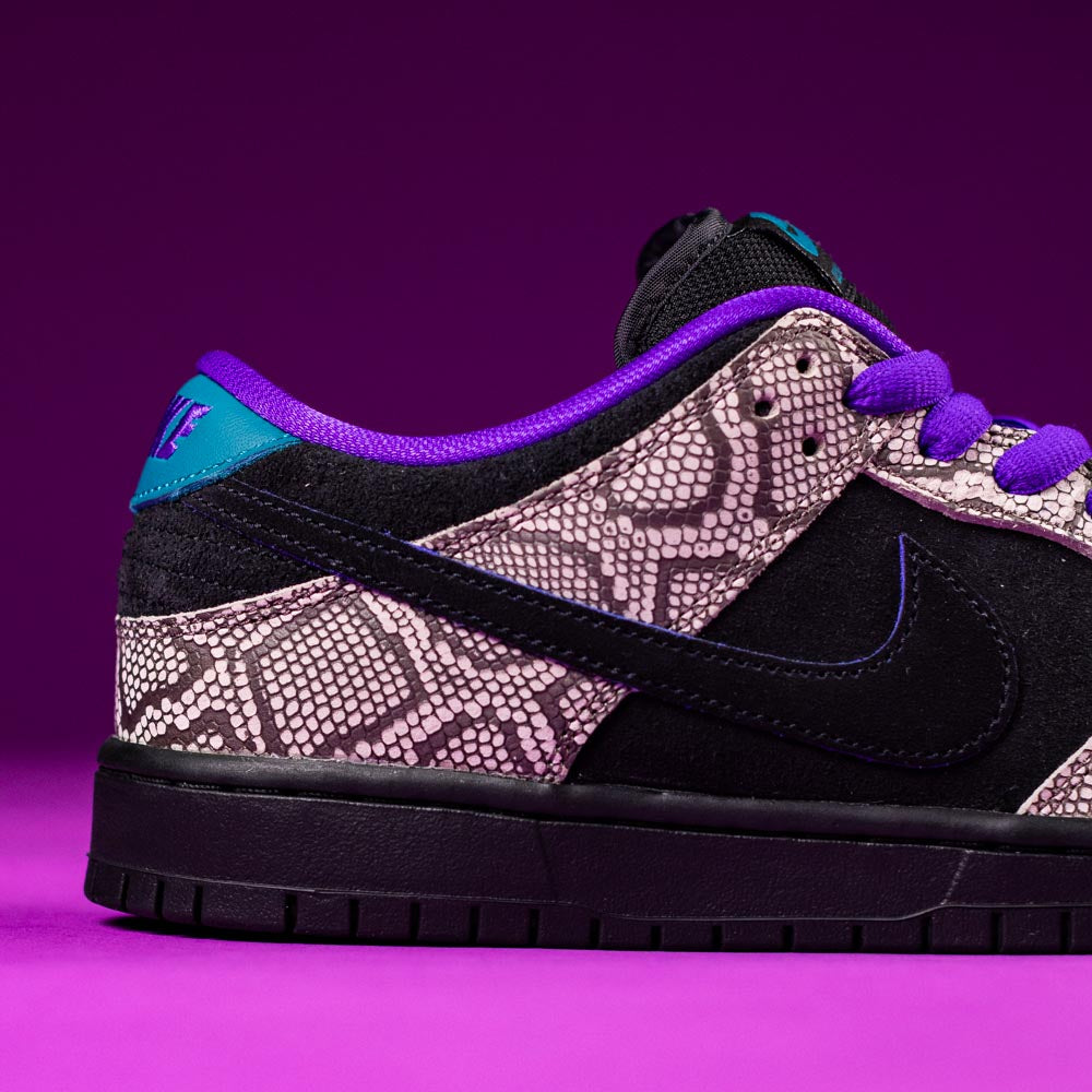 A close-up of the READ BELOW the BUTTON RAFFLE Nike SB Dashawn Jordan Dunk Low with snakeskin pattern, black suede, and purple accents, set against a vibrant purple background—perfect for your next Raffle Entry at Southside Skatepark.