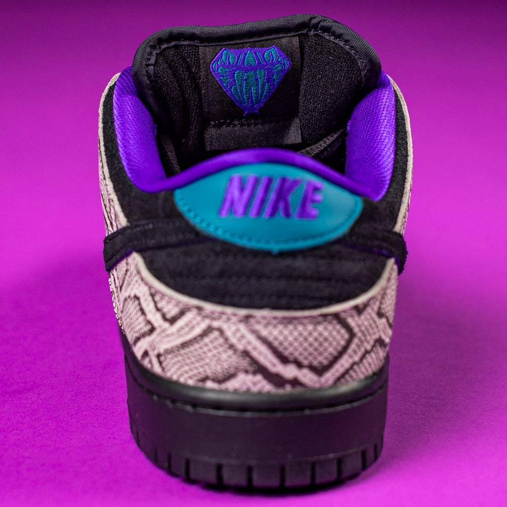 A close-up of the READ BELOW the BUTTON RAFFLE Nike SB Dashawn Jordan Dunk Low sneaker shows a snake print design, teal Nike heel logo, black midsole, purple lining, and a purple background for a Southside Skatepark raffle entry.