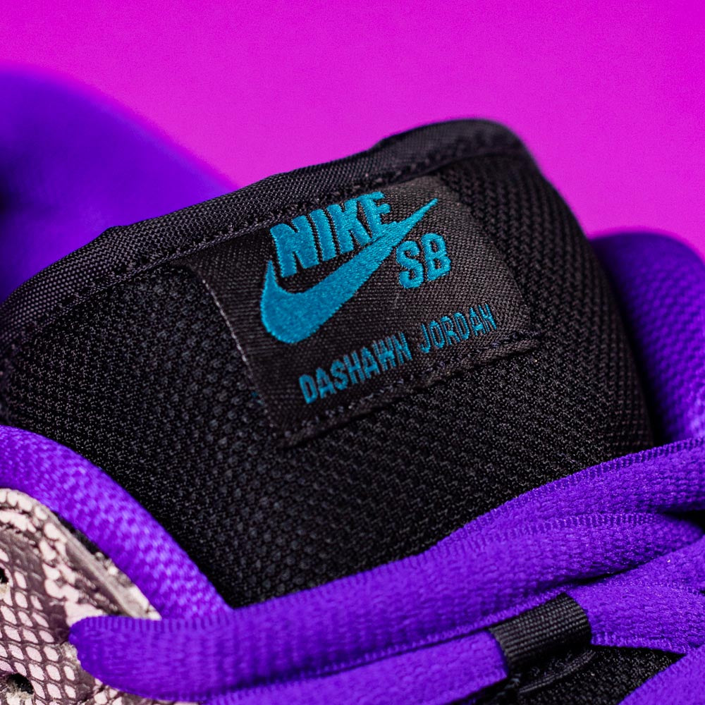 Close-up of the READ BELOW the BUTTON RAFFLE Nike SB Dashawn Jordan Dunk Low tongue with a teal Nike SB logo, black mesh, purple laces, and a bold look—perfect for your next Raffle Entry at Southside Skatepark.