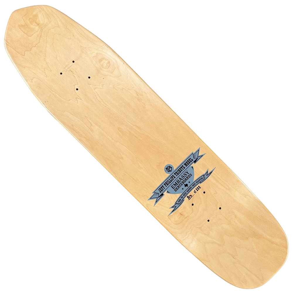 A natural wood Embassy Skateboards deck with “Don’t Mess with Texas” graphic, sized 8.5 x 33.2 in. This signed collectible skateboard features pre-drilled holes for trucks and makes a unique addition to any collection.