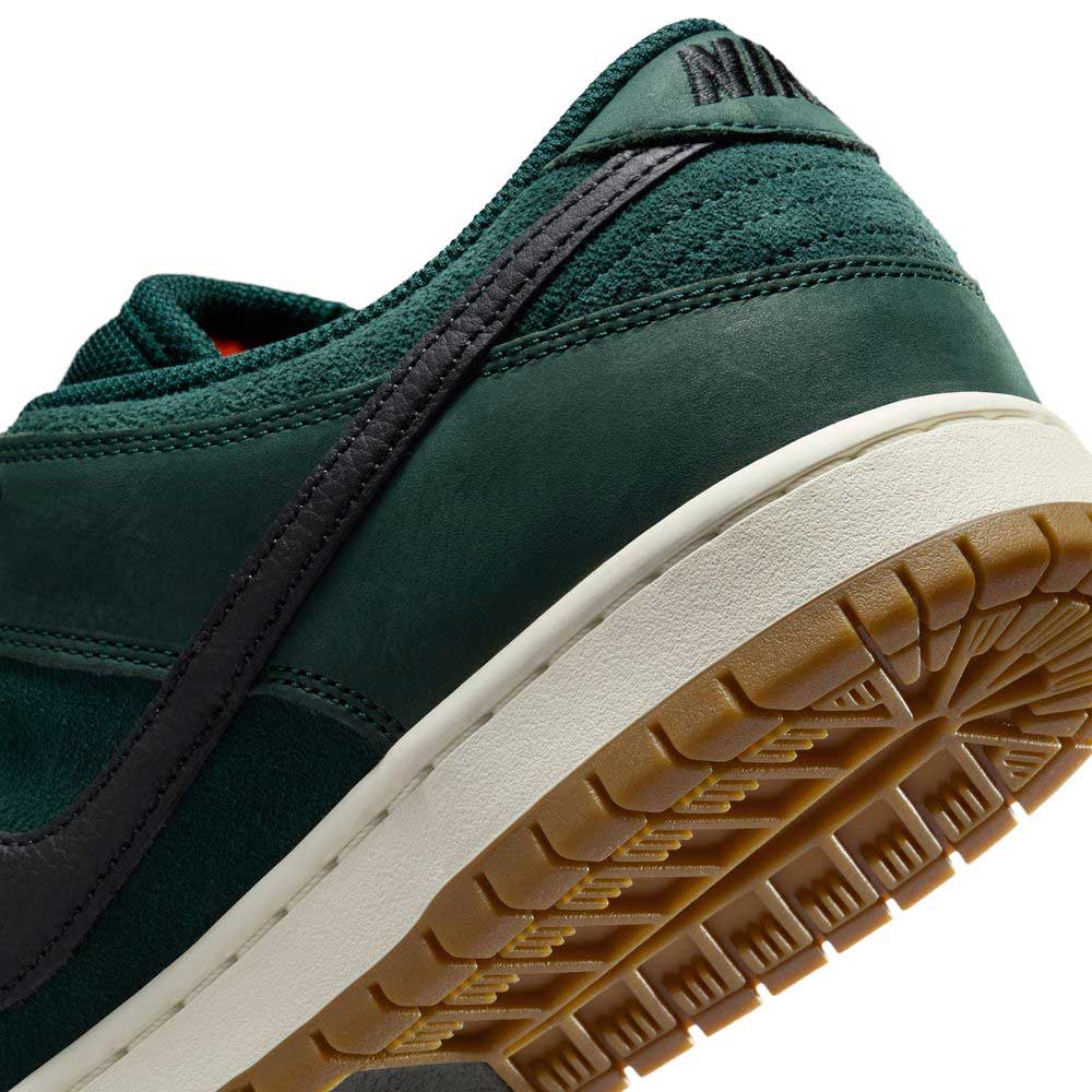 Close-up of the heel and sole of the Dunk Low Pro FJ1674300 Deep Fir Black Fir Sail Nike SB, featuring a green suede upper, black swoosh, sail midsole, and brown rubber outsole. The Nike logo appears on the heel tab.
