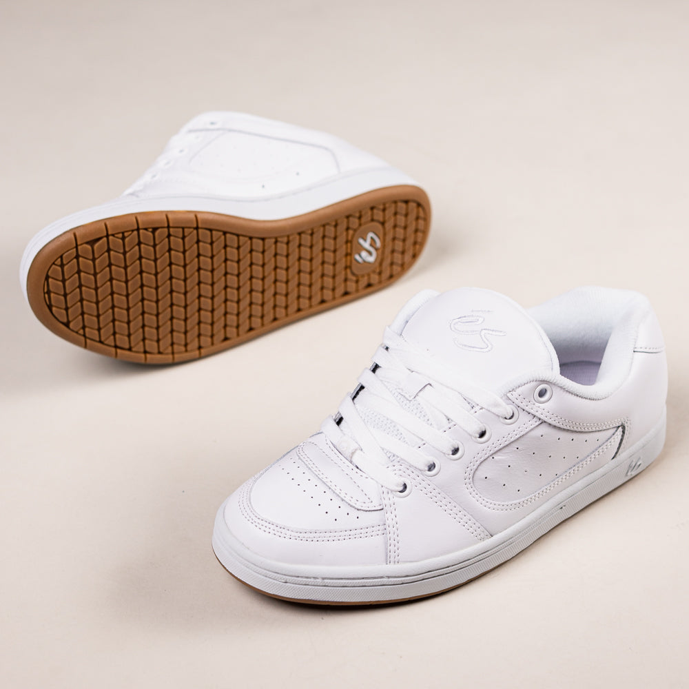 A pair of Accel White Leather Es Skateboarding Shoes with gum soles—one upright, one sole visible—are displayed against a light beige background.