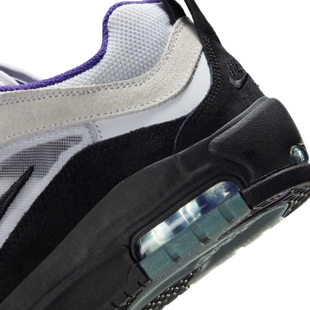 Close-up of the FB2393-104 White Black Court Purple Denim Air MAX Ishod Nike SB skate shoe, showcasing suede and leather upper, mesh details, black sole with Max Air cushioning, and an embroidered Nike logo on the heel.