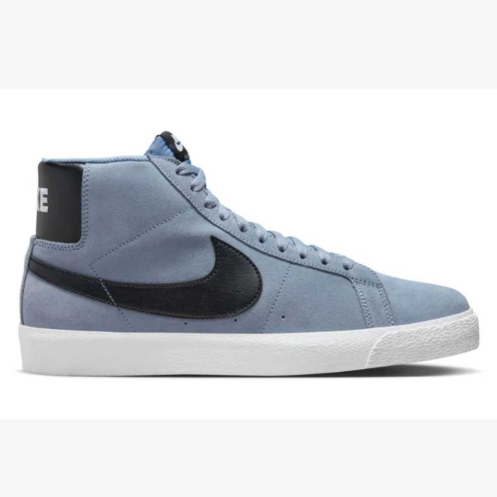 A side view of the FD0731401 Ashen Slate Blazer Mid Nike SB Suede Shoes with a blue upper, black swoosh and heel panel, white NIKE text on the back, a white rubber sole, and Zoom Air cushioning for responsive skateboarding comfort.
