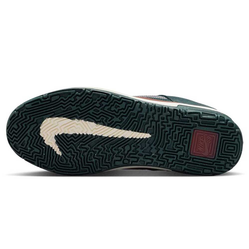 The image shows the sole of the FN4210-302 Seaweed Red Sepia Medium Ash YOUTH Day One GS Nike SB Shoes, featuring a dark green, maze-like texture, a large cream Nike swoosh, and a small maroon Nike SB Day One logo near the heel.