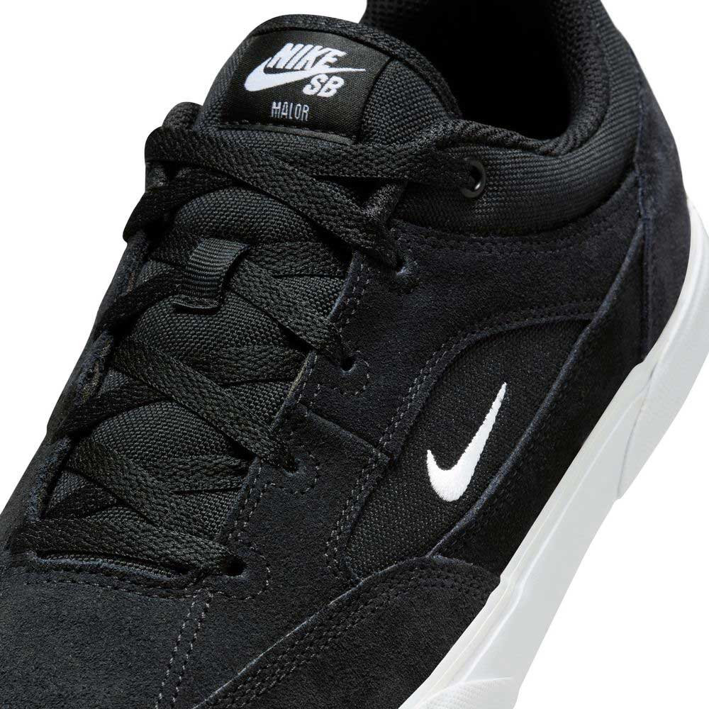 Close-up of FV6064001 Black White Malor Nike SB suede skateboarding shoe featuring a white swoosh and sole. The tongue displays NIKE SB and MAJOR branding in white text.