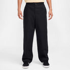 Wearing FV7349010 Double Knee Pant Black Nike SB Skateboarding, a loose-fit cotton twill skate pant, and black sneakers, person stands against a white background with only their lower torso and legs in frame.