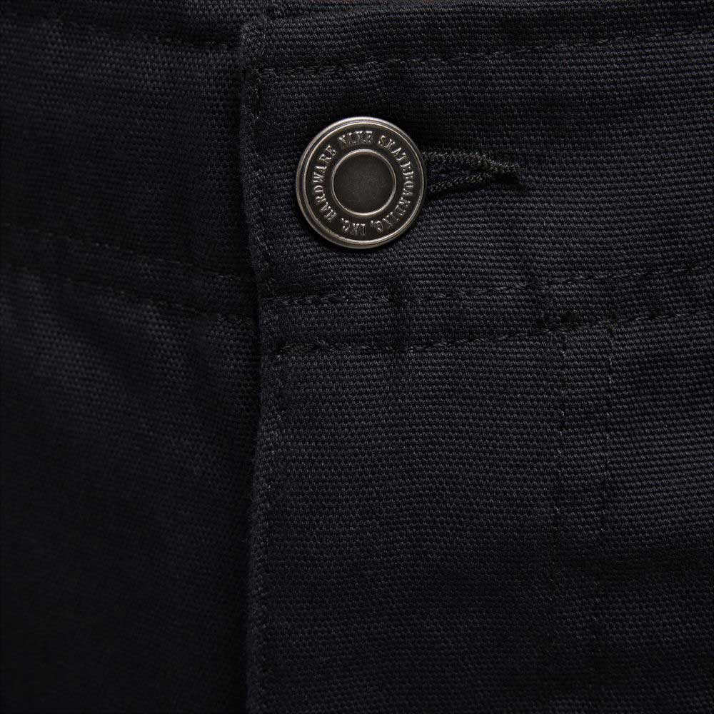 Close-up of the black cotton twill waistband on the FV7349010 Double Knee Pant Black Nike SB Skateboarding, featuring a metallic embossed button and visible stitching on sturdy skate pants with possible double knee reinforcement.