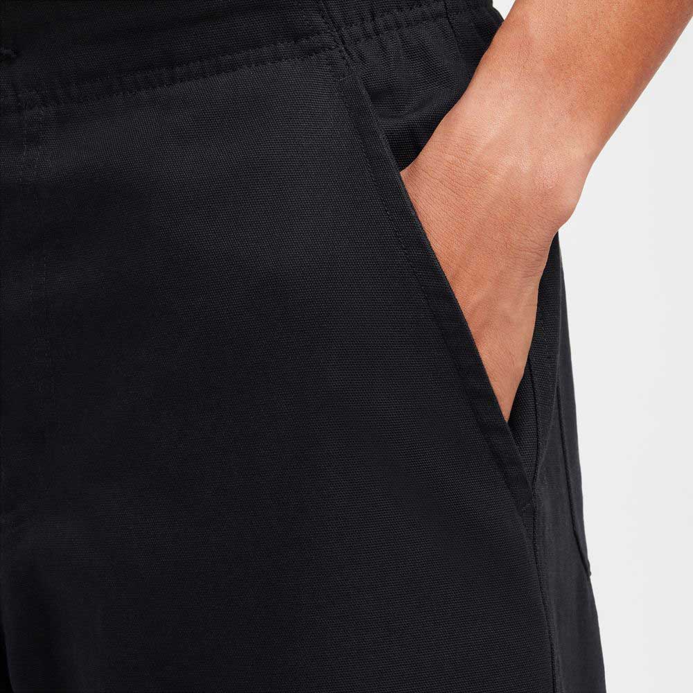 A close-up of a hand in the pocket of the FV7349010 Double Knee Pant Black Nike SB Skateboarding, made from durable cotton twill, with a blurred background.
