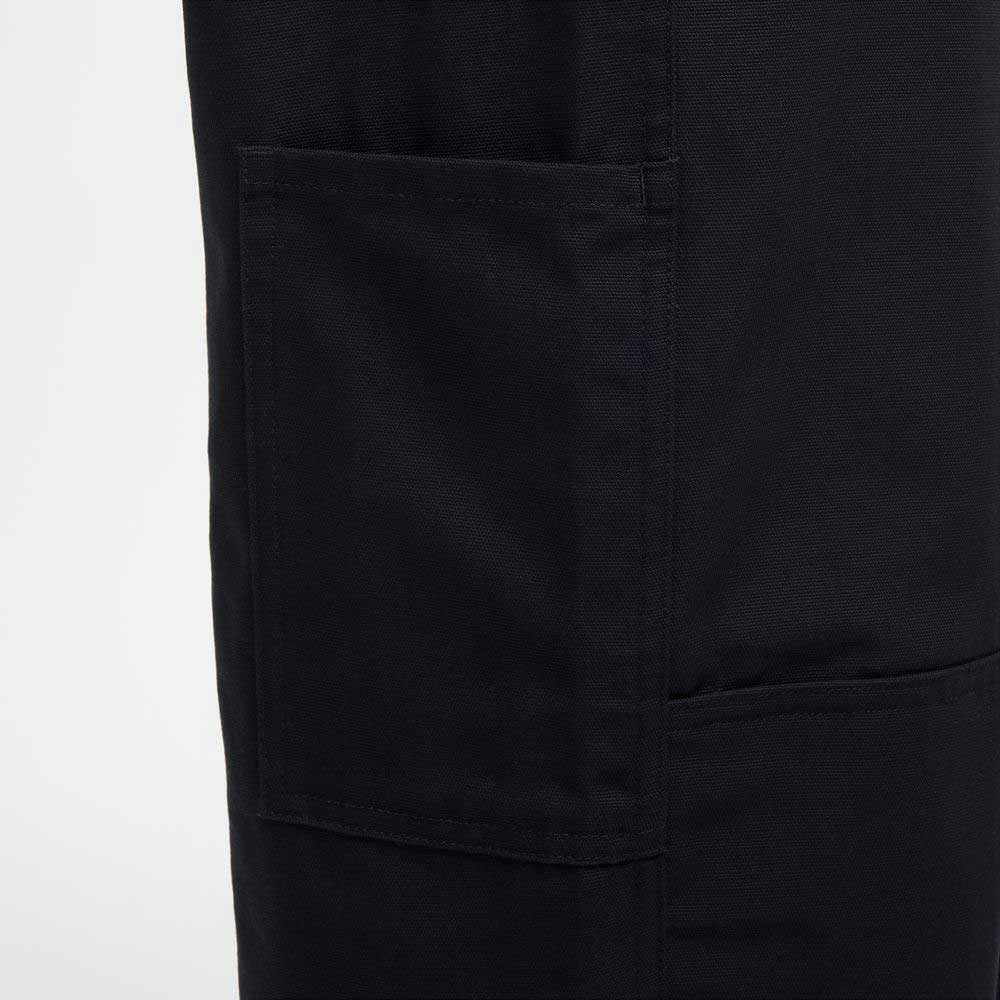 Close-up of the Nike SB Skateboarding FV7349010 Double Knee Pant in black cotton twill, showing a large rectangular patch pocket with visible stitching on the left side. The sturdy, slightly textured fabric contrasts against a light background.