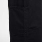 Close-up of the Nike SB Skateboarding FV7349010 Double Knee Pant in black cotton twill, showing a large rectangular patch pocket with visible stitching on the left side. The sturdy, slightly textured fabric contrasts against a light background.