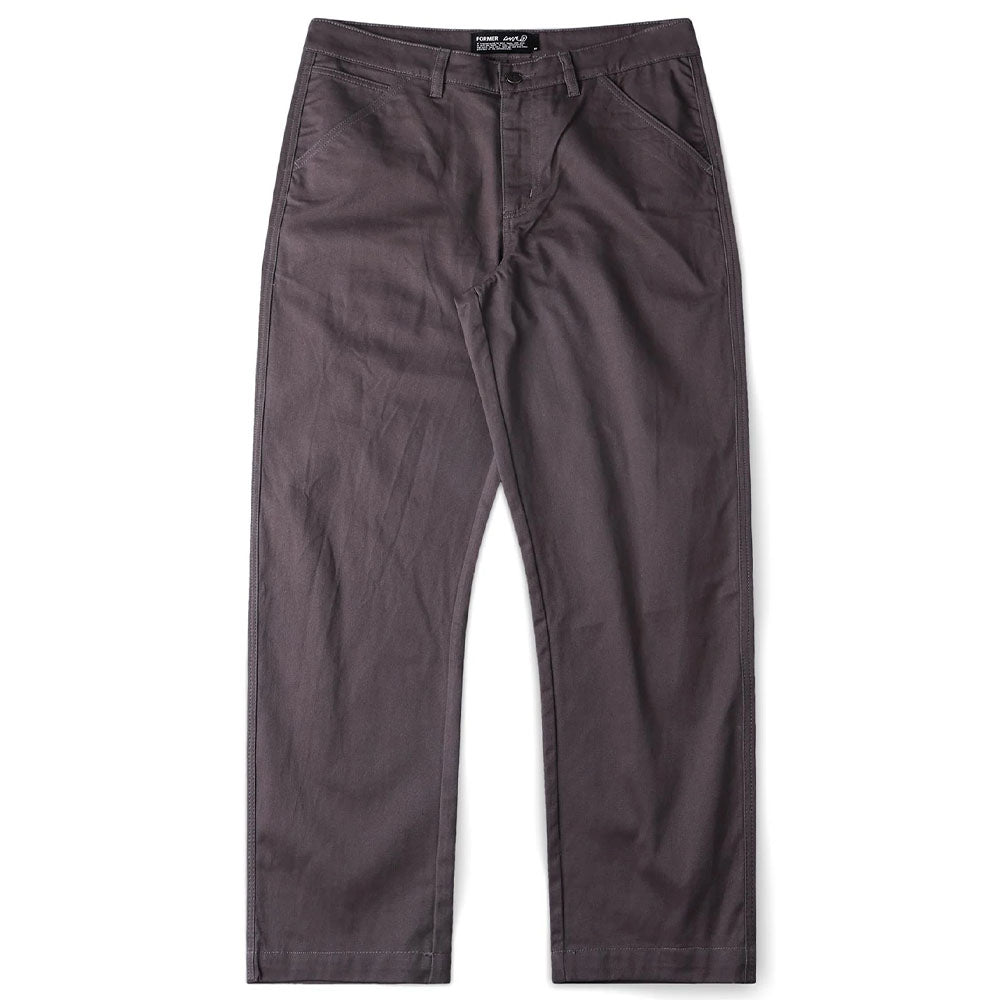 The Reynolds Work Pant Gunmetal Former is a pair of straight-leg, dark gray cotton twill pants featuring side pockets and a button closure, shown laid flat on a white background.