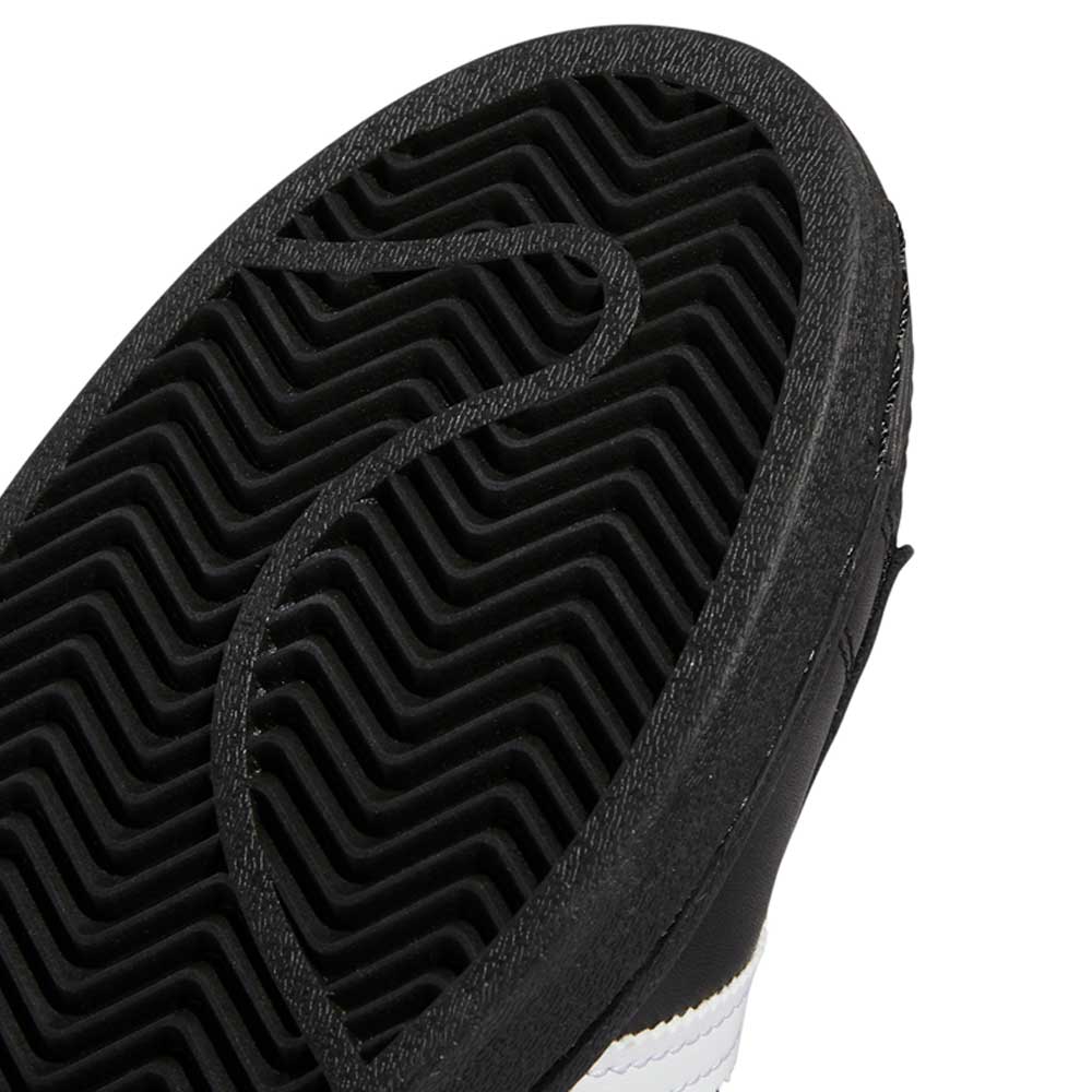 Close-up of the black rubber outsole on GW6931 Black White Superstar ADV Adidas Skateboarding Leather Shoes, showing a zigzag tread and circular grooves, plus part of the black and white upper—the ideal skateboarding footwear style.