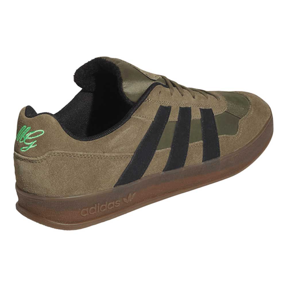 A gray and black Mark Gonzales KJ0281 Aloha Super suede skateboarding shoe by adidas, featuring a suede upper, classic black stripes, subtle accents, a gum sole, and unique embroidery on the heel. Inspired by iconic skate style, these adidas Aloha Super shoes are angled to showcase the side and back.